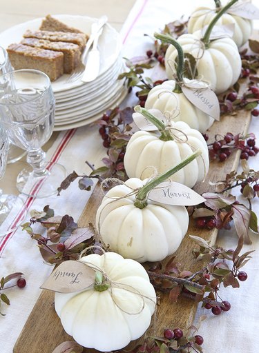 fall-inspired tablescape with mini white pumpkins and seasonal foliage