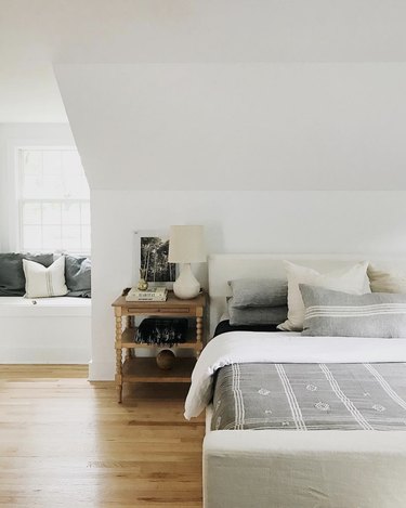 House Seven Design white bedroom with angled ceiling and upholstered bed frame