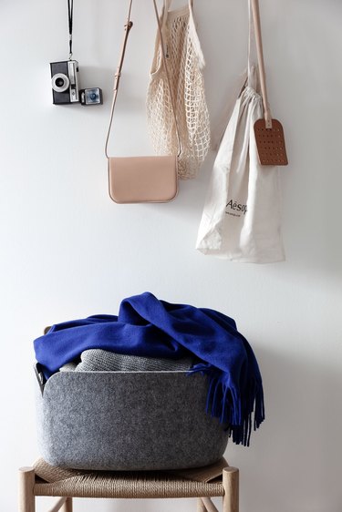 bedroom closet idea with accessories hanging from wall hooks and clothes folded in basket