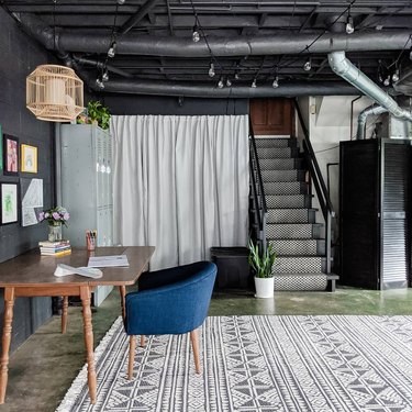 Black garage office with patterned rug and desk with blue chair