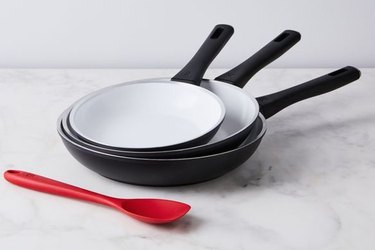 Stack of ceramic pans with red silicon spoon.