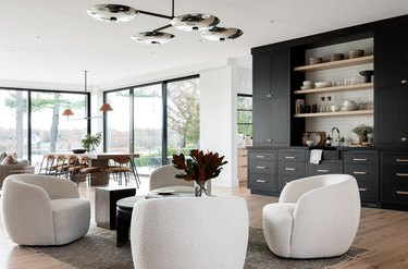 Four white lounge chairs, black built in wet Contemporary Bar, modern chandelier.