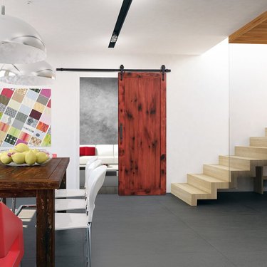 Red stained Contemporary Barn Doors, dark wood rustic dining table, white dining chairs, stairway, glass pendant lamps.