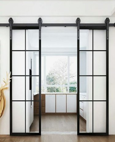 Glass and metal Contemporary Barn Doors leading into modern kitchen.