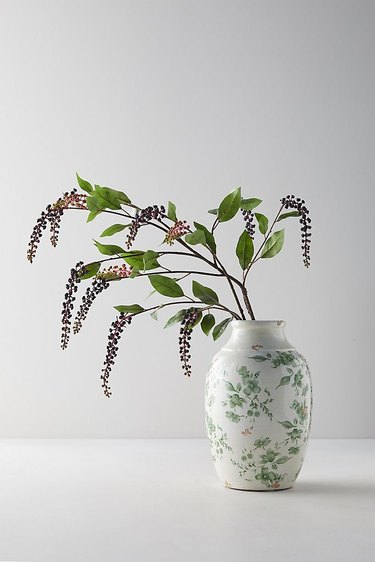 white backdrop with vase of winter berries for Christmas decorations list