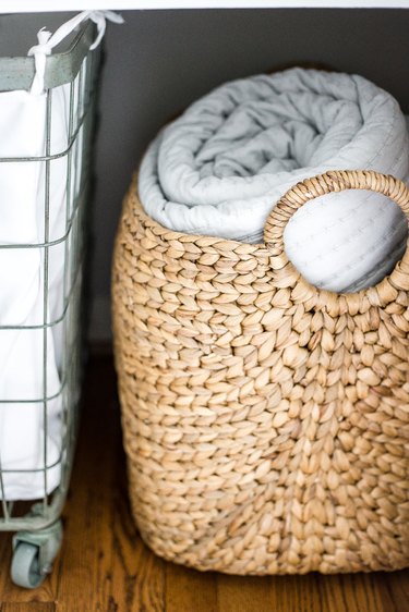 linen closet organization with hamper on wheels and basket with blanket
