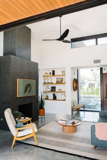 Midcentury living room style with black tile fireplace surround and concrete flooring