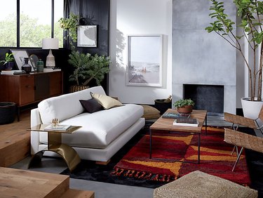 living room couch with large area rug and woven side chairs with brass side table