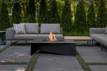 Black contemporary fire pit on outdoor patio next to seating