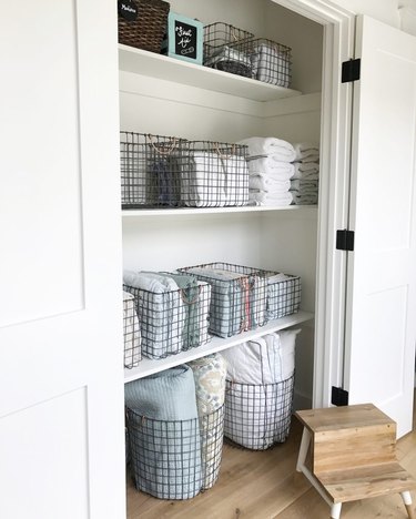 linen closet organization with wire baskets and bins filled with linens