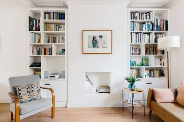 small living room idea for storage with floor-to-ceiling bookcases on either side of old fireplace that is now used for storage