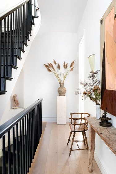 fall floral arrangement on white pedestal in hallway