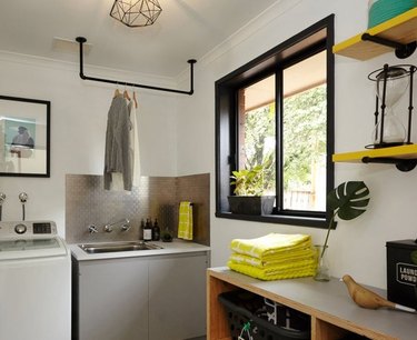 Garage Laundry Room with Washer, sink, clothes rack hanging over sink, shelves with towel.