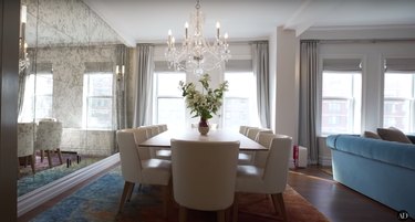misty copeland dining room featuring chandelier, white chairs, and textured mirror wall