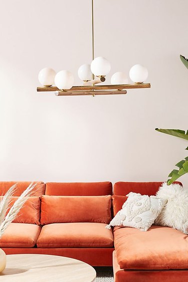 glam living room lighting idea with chandelier over velvet sectional sofa