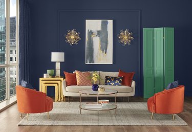 living room with navy walls and sofa and orange chairs