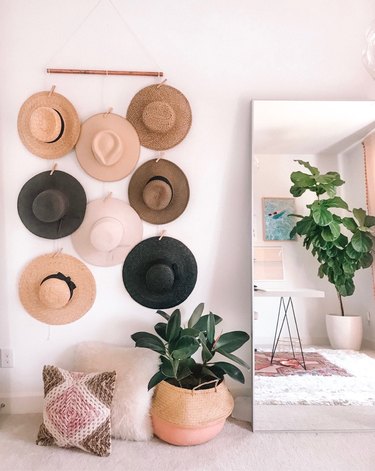 bedroom storage idea with hat wall hanging next to leaning mirror