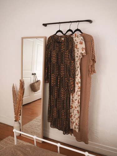 Bedroom storage ideas with towel rack hung on wall next to leaning mirror