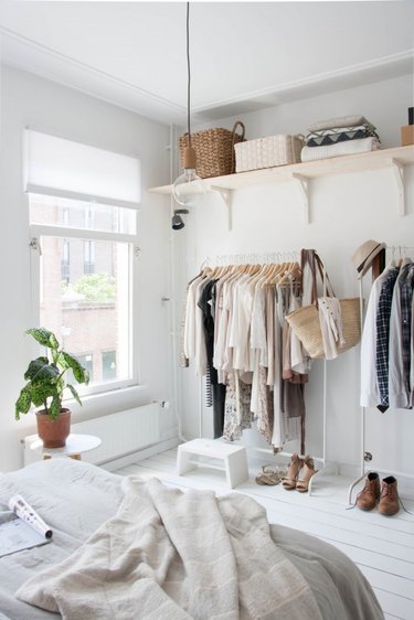 Bedroom storage idea with open shelving and freestanding clothing racks