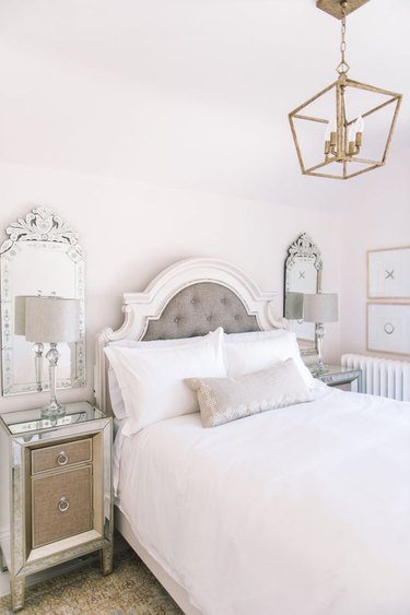 Mirrored decor in French country bedroom with pendant hanging over bed and tufted headboard