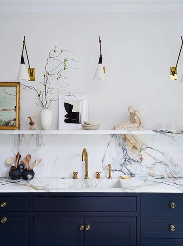 marble integrated kitchen sink with brass gooseneck kitchen faucet with blue cabinets and marble countertop