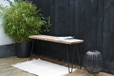 Modern outdoor bench with hairpin legs next to plant.