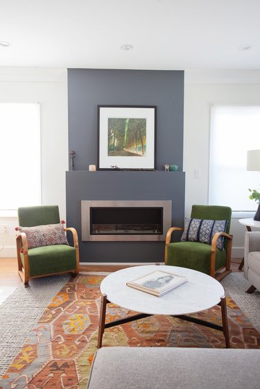 living room space in craftsman home with gray fireplace and green chairs