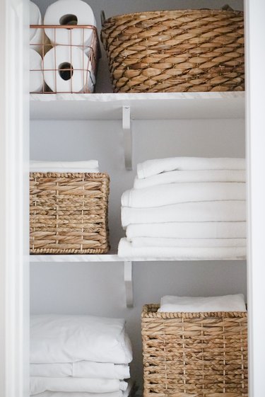 Linen Closet storage idea with neatly organized towels and woven bins