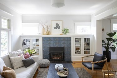 living room space in craftsman home with gray fireplace and green chairs