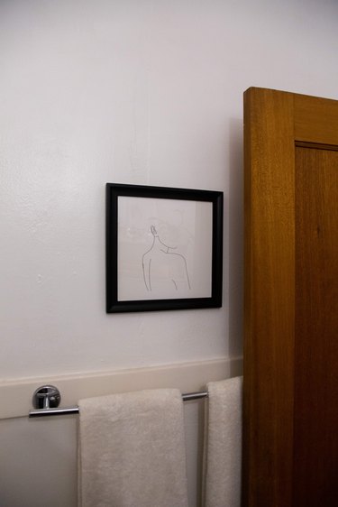 Bathroom door with art and hanging towels