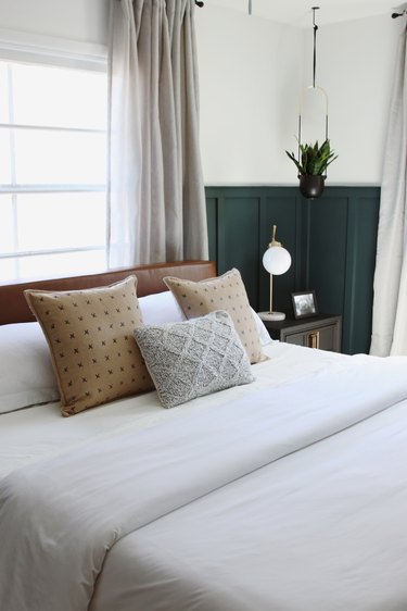 Modern bedroom style with green wainscoting and leather headboard in front of window