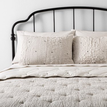 Target farmhouse decor with neutral bedding and iron headboard