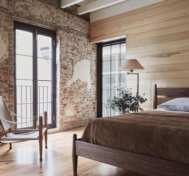 rustic bedroom with brick wall and wood paneling