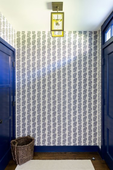 Wallpaper and bold colored doors brighten this hallway.