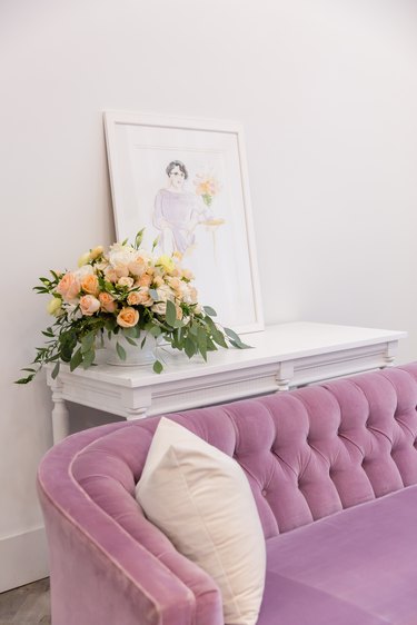 pink tufted sofa with white console table and framed artwork