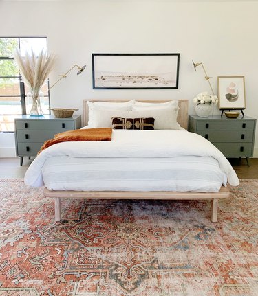 bohemian midcentury bedroom with patterned rug and wall sconces