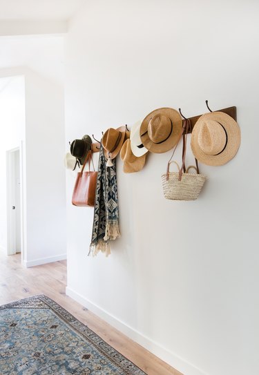 Hats and bags are organized on hooks in this hallway.
