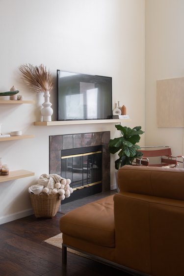 living room space with wood shelves, fireplace, and television 