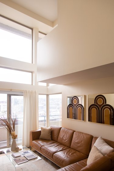 beige living room with brown sofa and artwork