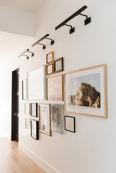 wall with artwork in various frames and lighting fixtures above