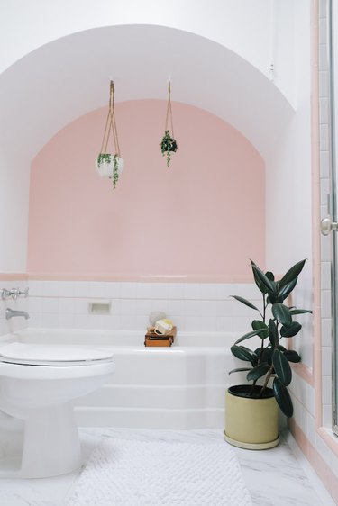 A bathroom with a pink accent wall