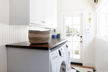 Laundry room with white walls and white cabinets