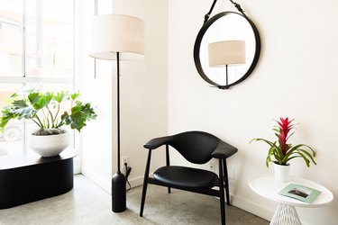 Black chair, black round mirror, plant and lamp