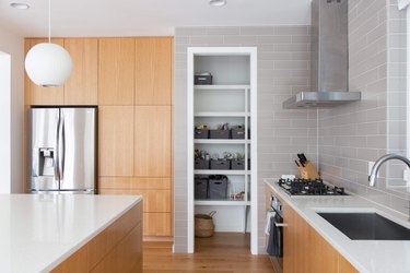 kitchen with light wood cabinet, taupe subway tile, open pantry