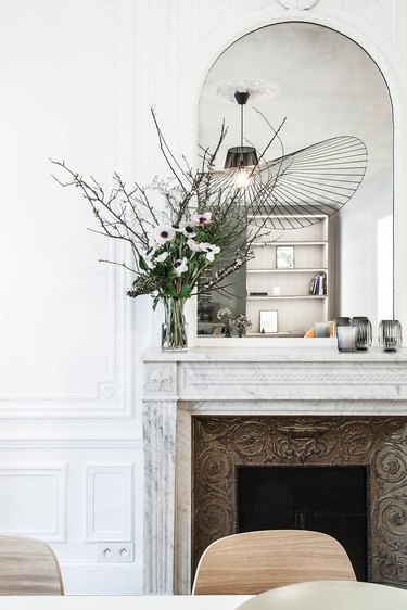 Contemporary apartment with antique fireplace and current light fixture