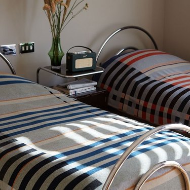 two beds with striped blankets and metal night stand in between