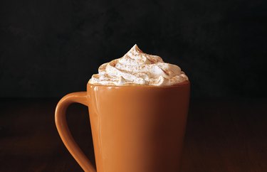 tall orange mug filled with pumpkin spice latte and whipped cream
