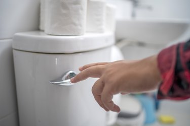 finger pushing button flushing toilet