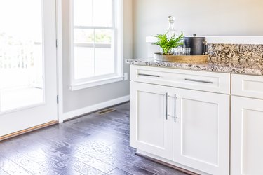 Modern clean wet bar with granite countertop cabinets, serving tray and door to balcony in staging of model house, home or apartment