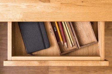 Notebook and pencils in open desk drawer top view